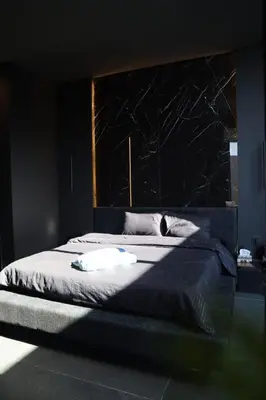 a bedroom with a large bed with a black wall at Deep House Villas in Al Rama