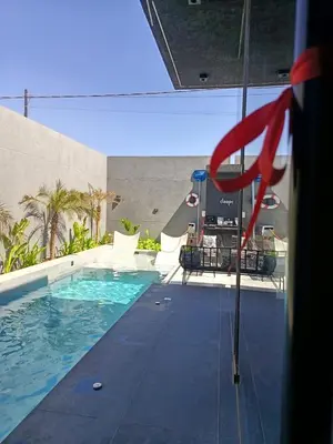 a swimming pool with some chairs and a red handle at Deep House Villas in Al Rama