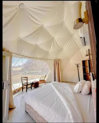 a bedroom with a tent with a table and chairs at Camb wadi Rum in Disah