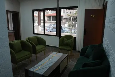 a waiting room with green chairs and a table at المتطورة للشقق الفندقية in Amman