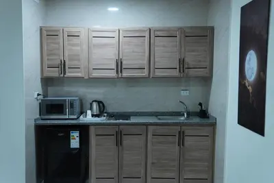a kitchen with wooden cabinets and a microwave at المتطورة للشقق الفندقية in Amman