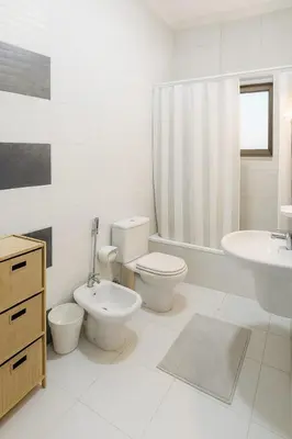 a white bathroom with two toilets and a sink at Family Deluxe Apartment in Amman