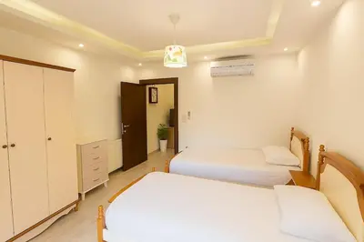 a small bedroom with two beds and a cabinet at Elite Apartment Compound 1 in Amman