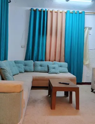 a living room with a couch and blue curtains at دار الخير للشقق المفروشة in Al Mafraq