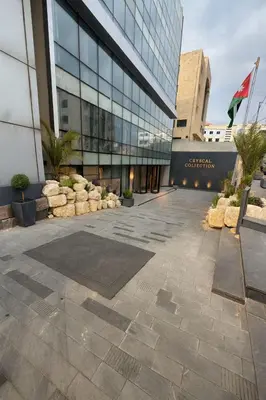 a large glass building with a courtyard in front of it at Crystal Collection Hotel in Amman