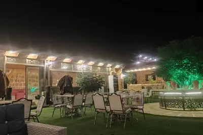 a group of tables and chairs in a yard at night at The modern village in ‘Ayn Amūn