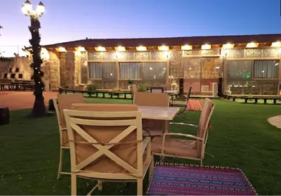 a patio with a table and chairs in the grass at The modern village in ‘Ayn Amūn