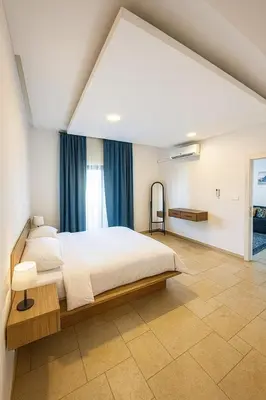 a bedroom with a large white bed and blue curtains at Rainbow Street Studio Cozy Central in Amman