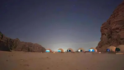 a group of domes in the desert at night at Wadi Rum cloud in Ma‘ān