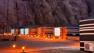 a building with lights in front of a mountain at Wadi Rum cloud in Ma‘ān