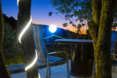 a table and a chair on a porch with a sunset at Sultan Chalet Ajloun شاليه السلطان in Ajloun