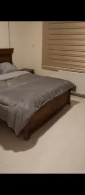 a bed with a wooden frame in a bedroom at شقه مفروشه بالكامل في عمان شارع مكه ضاحيه الأمير راشد in Amman