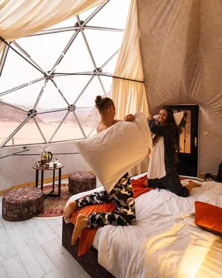 two people standing on beds in a tent at BUBBLES LUXURY CAMp in Wadi Rum