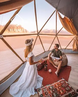 a woman and a man sitting in a tent at BUBBLES LUXURY CAMp in Wadi Rum