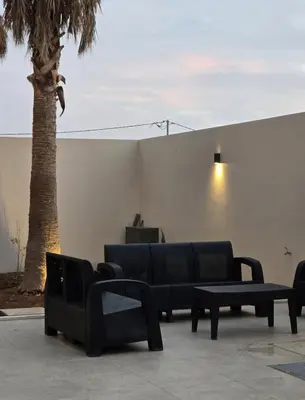 a group of chairs and tables next to a palm tree at RV Villas Deadsea in Sowayma