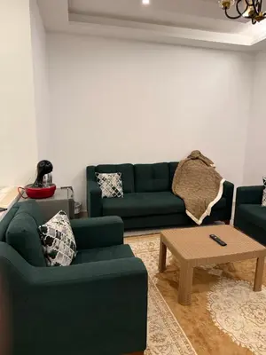 a living room with two green couches and a coffee table at Rooftop sport city in Amman