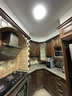 a kitchen with wooden cabinets and a stove top oven at Cozy Studio 1 Central Amman Near Rainbow Street in Amman