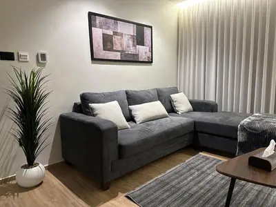 a living room with a gray couch and a plant at Cozy Modern Apartment Damac Abdali in Amman
