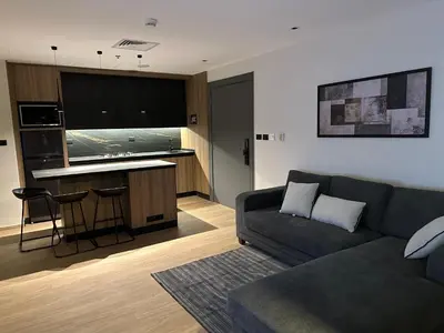 a living room with a couch and a kitchen at Cozy Modern Apartment Damac Abdali in Amman