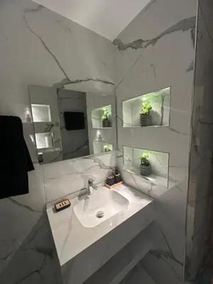 a white bathroom with a sink and a mirror at Cozy Modern Apartment Damac Abdali in Amman