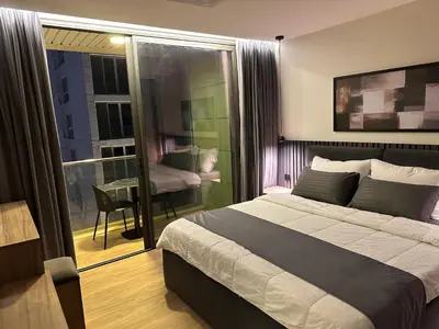 a bedroom with a bed and a balcony with a table at Cozy Modern Apartment Damac Abdali in Amman