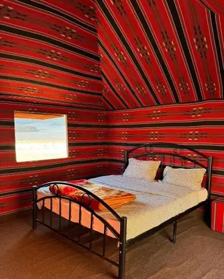 a bed in a room with a red wall at Wadi Rum Bedoun in Wadi Rum