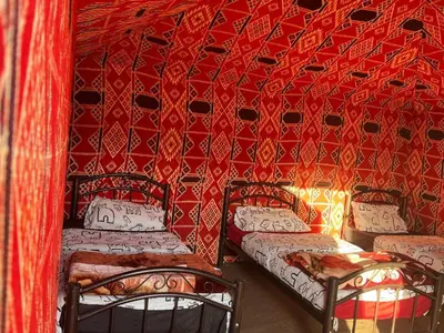 two beds in a room with a red wall at Wadi Rum Bedoun in Wadi Rum