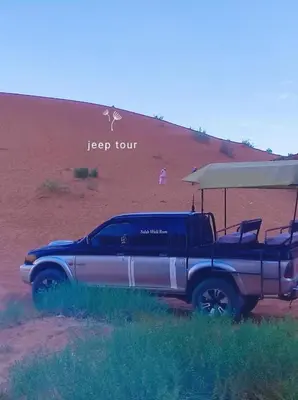 a truck parked on a dirt road with an umbrella at Oasis of Civilizations Camp in Wadi Rum