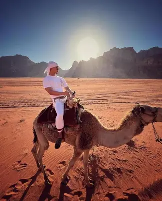 a man riding a camel in the desert at Oasis of Civilizations Camp in Wadi Rum