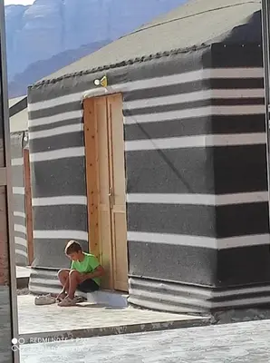 a boy sitting on the steps of a building at Oasis of Civilizations Camp in Wadi Rum