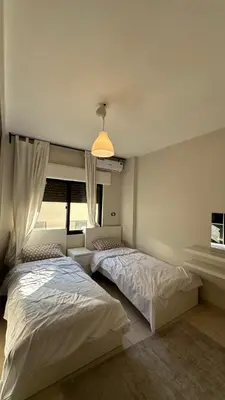 a bedroom with two beds and a window at Modern 2BR Apartment in Deir Ghbar in Amman