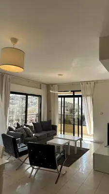 a living room with a couch and a table at Modern 2BR Apartment in Deir Ghbar in Amman