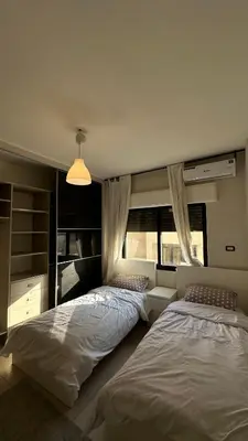 a bedroom with two beds and a window at Modern 2BR Apartment in Deir Ghbar in Amman