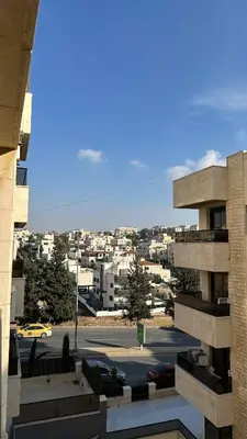 a view of a city from a building with a parking lot at Modern 2BR Apartment in Deir Ghbar in Amman
