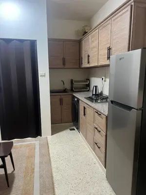 a kitchen with wooden cabinets and a refrigerator at Cozy Studio Apartment in Amman