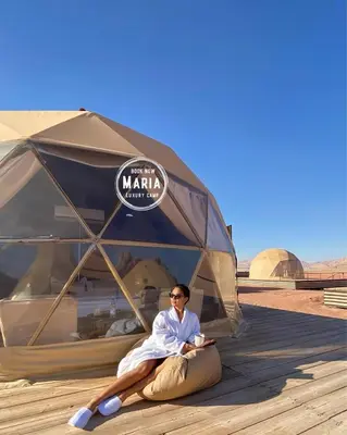 a woman laying in a tent in the desert at MARIA LUXURY CAMp&BUBBLES ROOM in Wadi Rum
