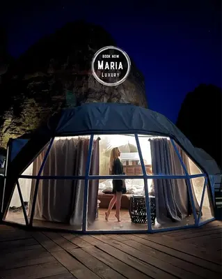 a woman walking in a gazebo on a dock at MARIA LUXURY CAMp&BUBBLES ROOM in Wadi Rum