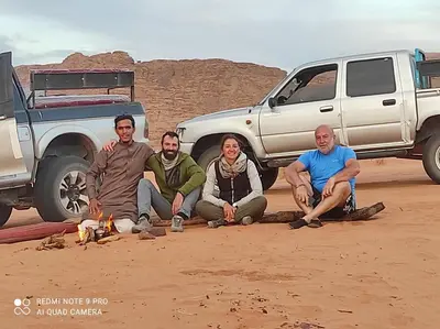 a group of people sitting in front of a truck at Oasis of Wonders Camp in Wadi Rum