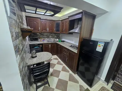 a kitchen with wooden cabinets and a black refrigerator at Cozy Studio 2 Central Amman, Near Rainbow Street in Amman