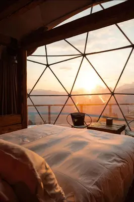 a bed in a room with a view of the sunset at Magic rum luxury camp in Wadi Rum