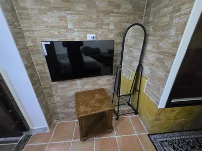 a tv on a brick wall with a table and a mirror at Studio 3 Cozy Amman Central Near Rainbow Street & First Circle in Amman
