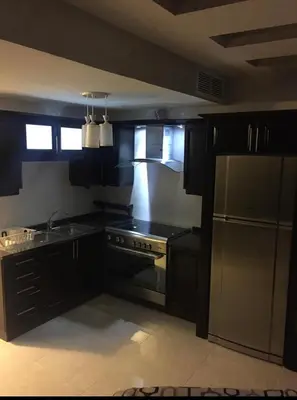 a kitchen with black cabinets and a stainless steel appliance at شقة مفروشة للإيجار بالرابية بالقرب من السفارة الصينية in Amman