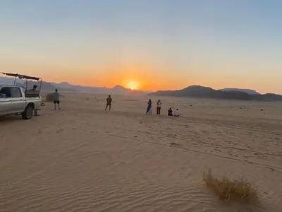 a group of people standing in the desert watching the sunset at Ahmad Wadi Rum Camp in Wadi Rum