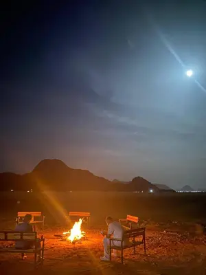 a group of people sitting around a fire at night at Ahmad Wadi Rum Camp in Wadi Rum