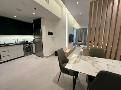 a kitchen and living room with a table and chairs at Damac Amman Modern Luxury Apartment in Amman