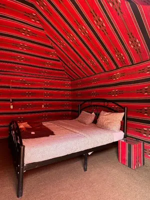 a bed in a room with a red wall at Wadi Rum Bedouin in Wadi Rum