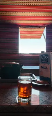 a glass of tea and a pack of milk on a table at Nature rum camp in Wadi Rum