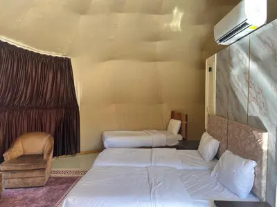 a room with two beds and a chair in it at Wadi Rum Al-Hadi camp in Disah