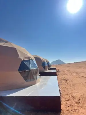 three tents are lined up in the desert at Wadi Rum Al-Hadi camp in Disah