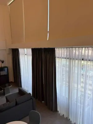 a living room with a couch and a large window at DAMAC AMMAN LUXURY APARTMENTs داماك عمان شقق فاخرة in Amman